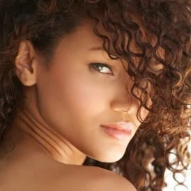 Portrait of a woman with curly hair looking over her shoulder, showing her natural profile