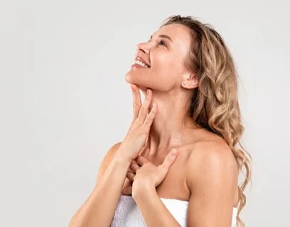 Smiling woman with wavy blonde hair touching her neck and jawline, side view