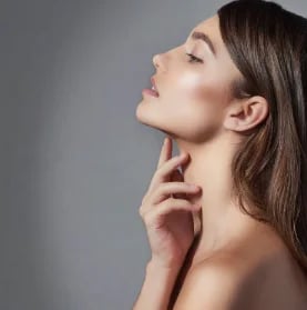 Woman in profile with her fingertips at her neck, showing a smooth jawline and neck