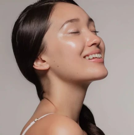 Woman in profile with dark hair pulled back into a braid, eyes closed and smiling
