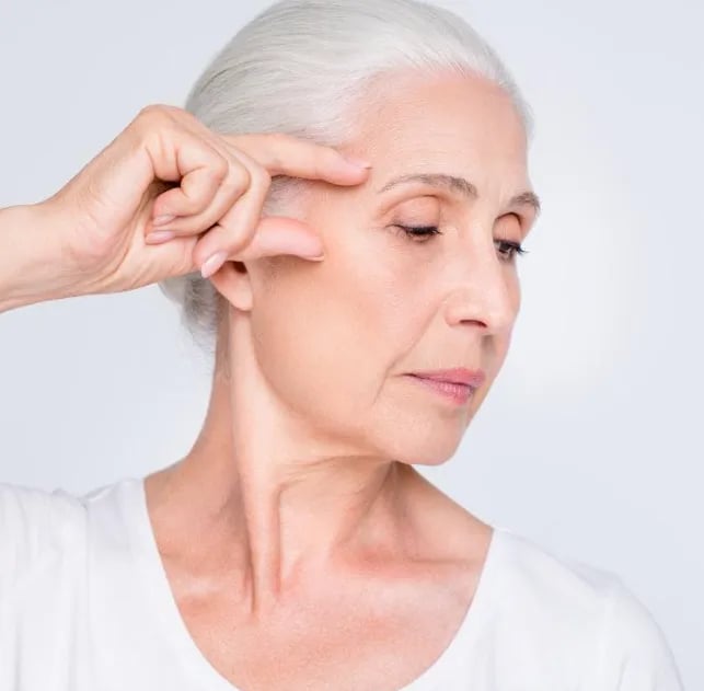 Woman in her forties touching her temple where volume loss shows