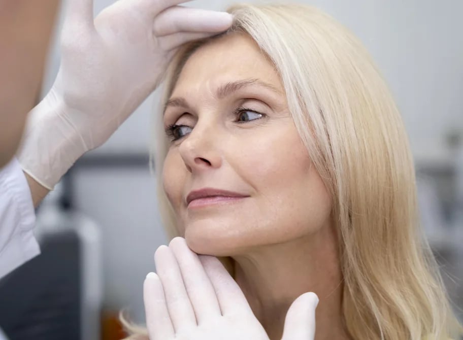Clinician assessing a patient's facial skin laxity by hand during an in-person XERF™ candidacy evaluation